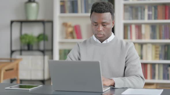African Man Working on Laptop in Library
