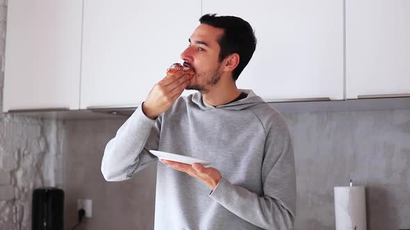 Young man eating donut at kitchen