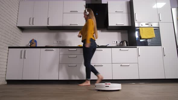 Woman Dancing in Kitchen While Robot Cleaning