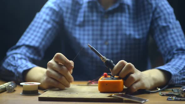 Man Repairman Is Doing Soldering Work While Sitting at Table in Technical Center