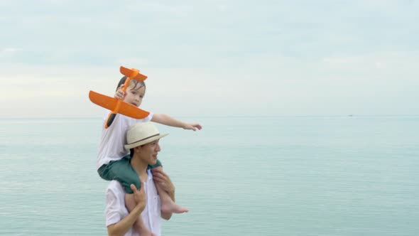 Happy asian family having fun and cheerful with father and son straightened arm and holding a plane.
