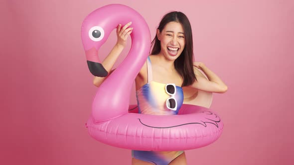 Beautiful Sexy asian woman in bikini and smiling standing  on pink background