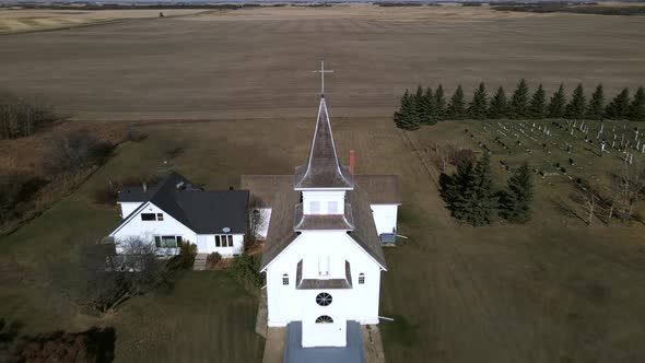 Backwards flying aerial footage revealing pretty St Boniface church in remote location. White old wo