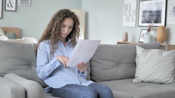 Curly Hair Woman Reading Documents While Sitting on Couch