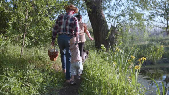 Loving Family Grandparents with Their Cute Grandchild in Hats Have Fun Walking Outdoors Among Trees