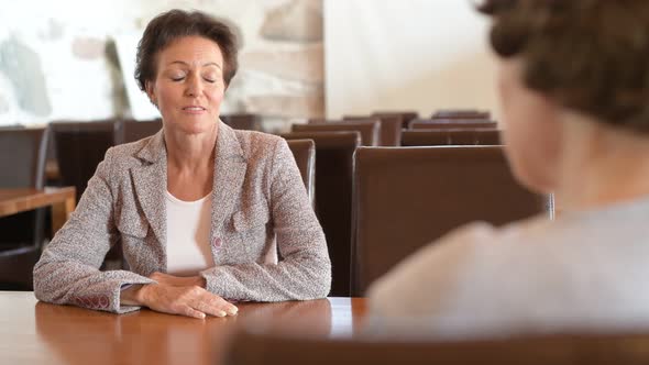 Happy Mature Businesswoman Talking With Senior Woman At The Coffee Shop