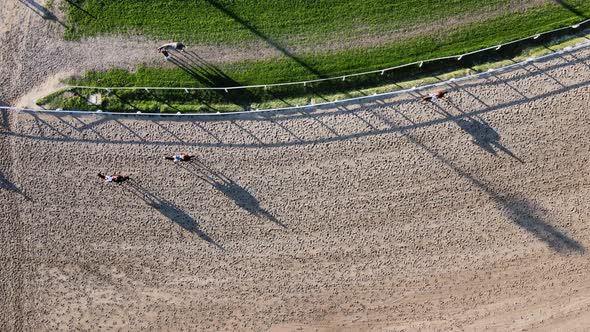 Vertical straight down view at trainers on horseback with horses galloping on the racecourse at Hipo