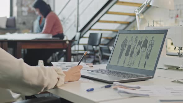 Woman Looking at Fashion Sketches and Working on Collection