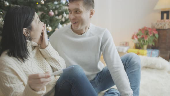 Portrait of Excited Couple Looking at Positive Pregnancy Test on New Year's Eve