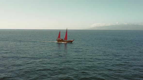 An Old Ship with Crimson Sails Is Sailing on the Open Ocean To Meet Adventures