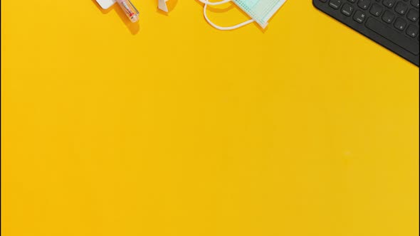 Stationery Keyboard Masks and Hand Sanitizer Appear Against Orange Table