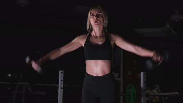 Slender Girl Trains Her Arms with Dumbbells