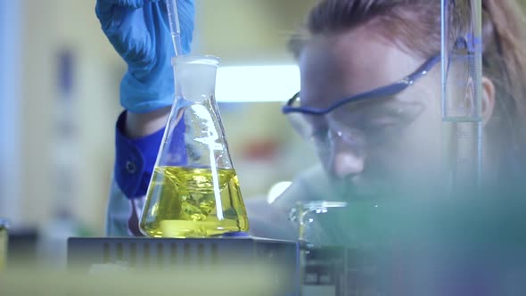 Female Chemist Pour Liquid in Flask with Pipette