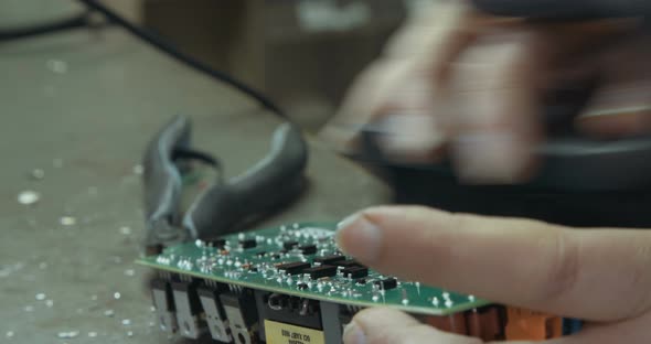 Worker inspecting and soldering electronic boards