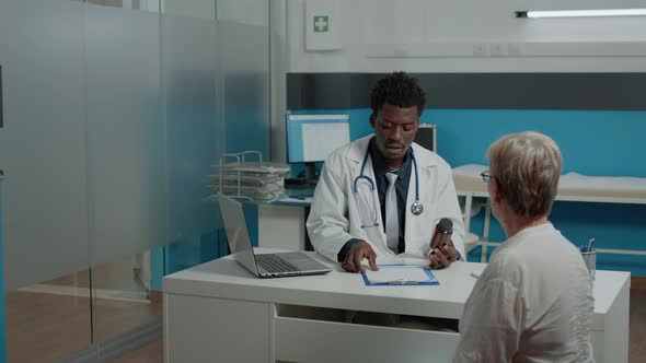 Adult Doctor of African Ethnicity Giving Bottle of Pills