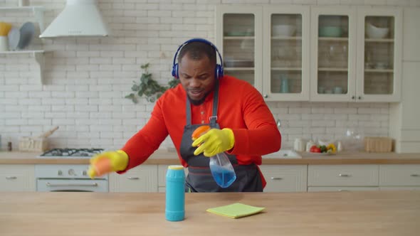 Positive African Man in Headphones Housekeeping in Kitchen