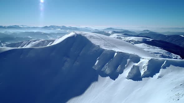 Flight over the turquoise snowy mountains illuminated by the day sun