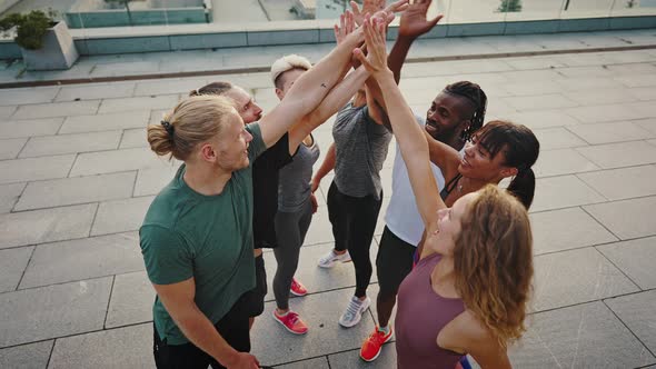 Multiracial Group of Athletes Men and Women in Sports Uniforms Doing a High Five After Completing a