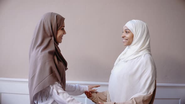 Two Muslim Girls Hugging and Smiling in Beige Studio