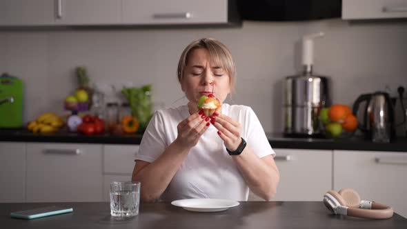 Sweet Tooth Female Eating Cupcake in Kitchen