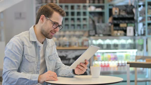 Video Call on Tablet By Man in Cafe