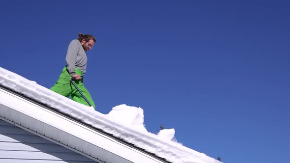 Removing Fresh Snow From a Roof in a Sunny Winter Day