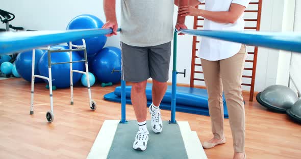 Physiotherapist Helping Patient Walk with Parallel Bars