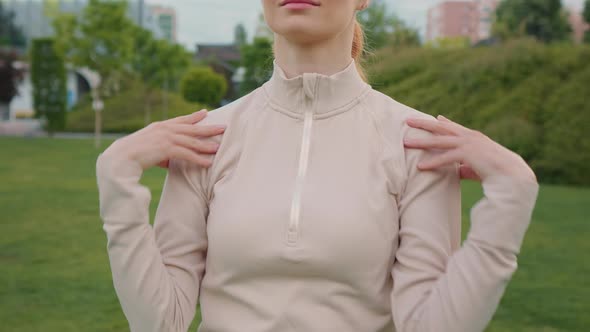 Woman doing warm up exercise rotating shoulders in the park, sport as routine.