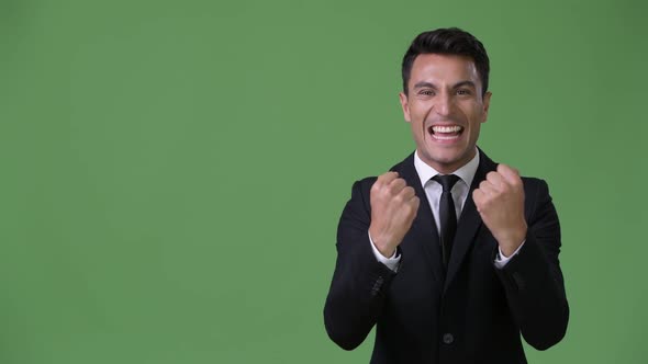 Young Handsome Hispanic Businessman Against Green Background