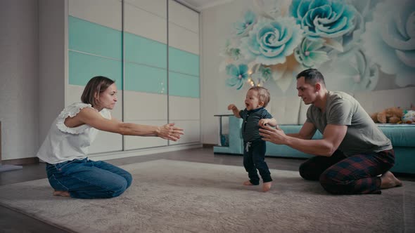 Happy Family Smiling As Baby Takes First Steps