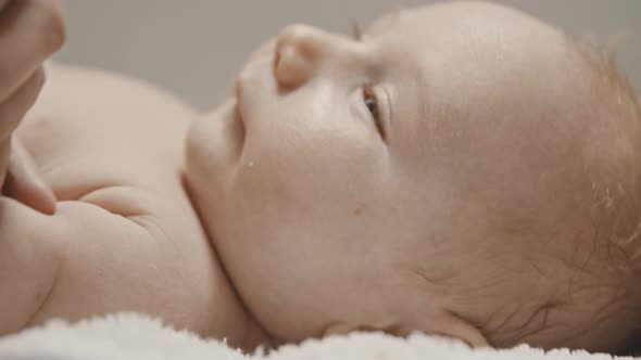 A Little Baby Lying in Bed and His Mother Turns Him To the Side