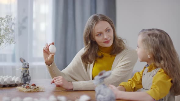 Mother Showing White Egg to Daughter and Talking