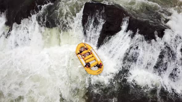 Aerial drone top view of a yellow rafting boat attempting to move down a waterfall on the Nile River