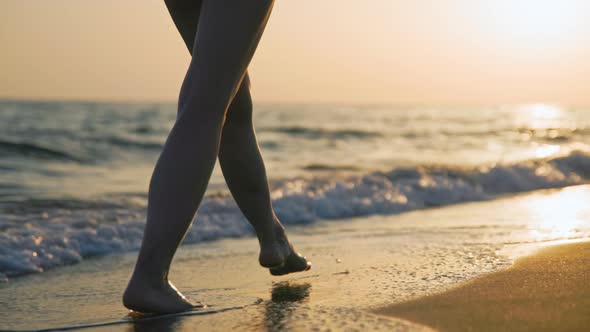 Walking barefoot girl in a summer dress at sunset
