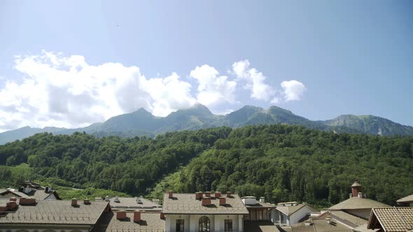 Rooftops of Ski Resort with Mountains in Background. Panorama of Forest-capped Mountain Peaks on