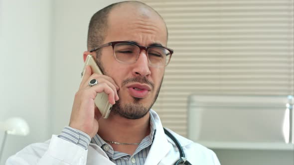 Young Male Doctor in Glasses Talking on Mobile Phone