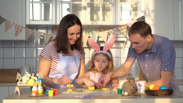 Family of Three Cutting Easter Cookies in Kitchen