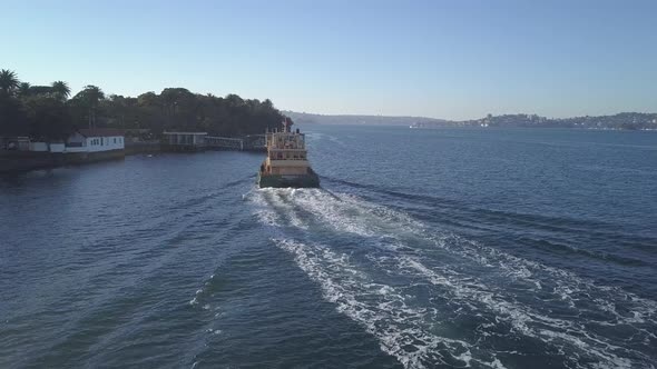 Sydney ferry docking at suburb port in summer, low aerial follow