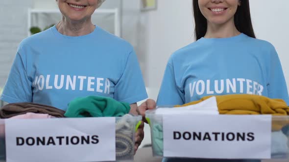 Kind Ladies Volunteers Showing Boxes With Clothing to Camera Donations for Poor