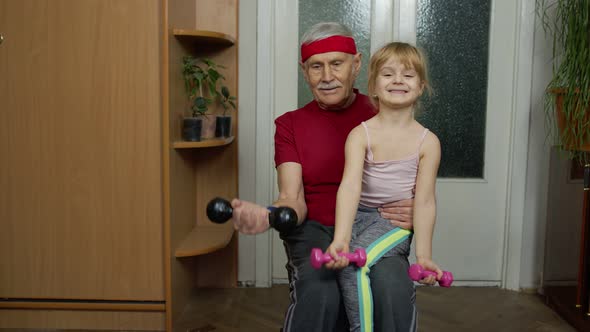 Active Grandfather Senior Man with Child Girl Doing Fitness Weight Lifting Exercises with Dumbbells