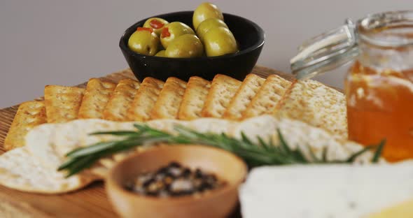 Bowl of green olives, spices, crispy biscuits, jam, rosemary herb, cheese and walnuts