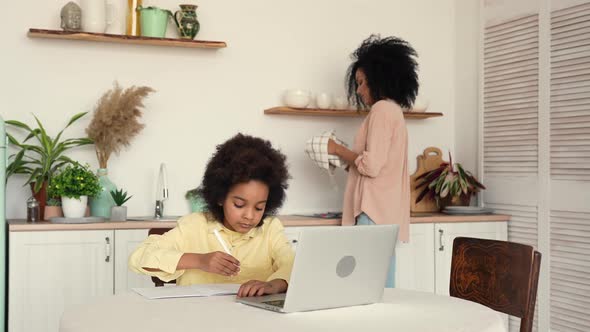 Little Focused Afro American Schoolgirl Studying Remote Online From Home Using Laptop
