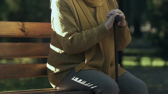 Upset Old Woman Sitting With Walking Stick in Park, Lack of Social Benefits