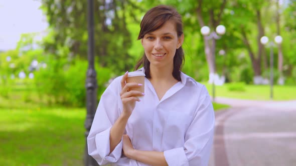 Young Female in White Shirt Drinking Coffee Walk on the Street in Summer Season