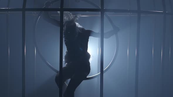 Girl Acrobat in a Cage Spinning on the Air Hoop