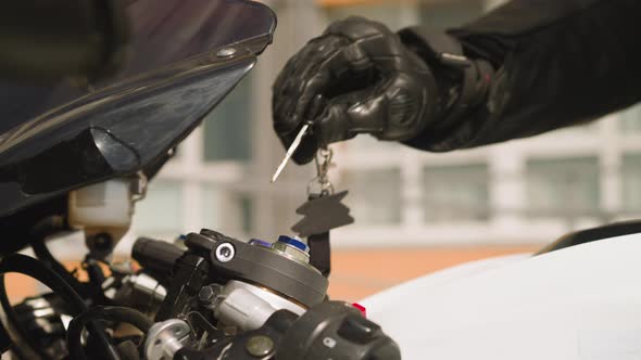 Biker Puts Key to Ignite Motorcycle on Parking Lot Closeup