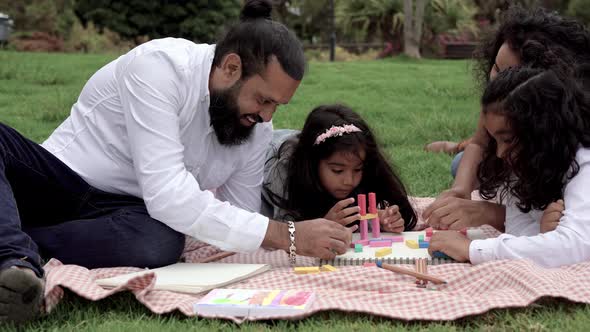 Indian parents and children having playful time at city park with wood toys