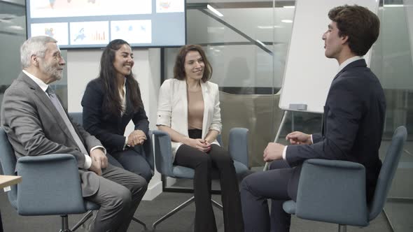 Group of Smiling Employees Sitting on Chairs and Talking