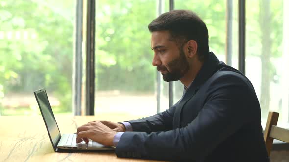 Serious Confident Young Indian Man Entrepreneur in Formal Suit Working on a Laptop