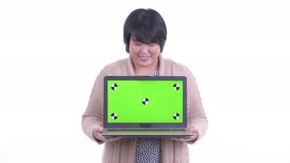 Happy Overweight Asian Woman Thinking While Showing Laptop Ready for Winter